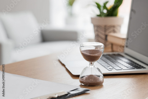 Hourglass with laptop on de...