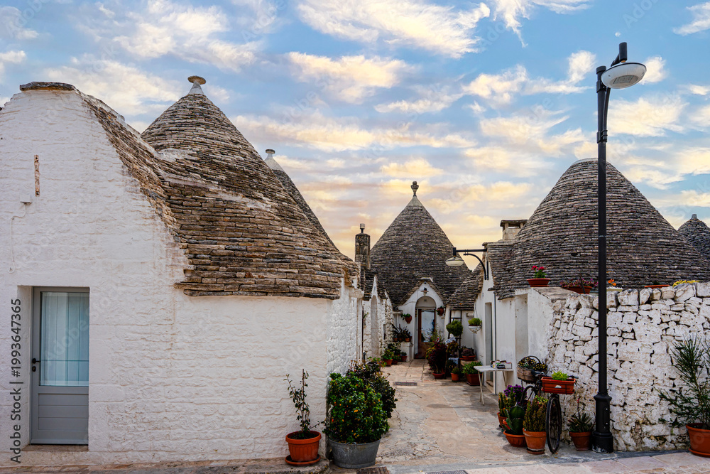 Fototapeta premium Alberobello miasto we Włoszech, słynie z unikatowych form budownictwa – domów typu trulli, które są okrągłe i mają stożkowate dachy z kamienia.