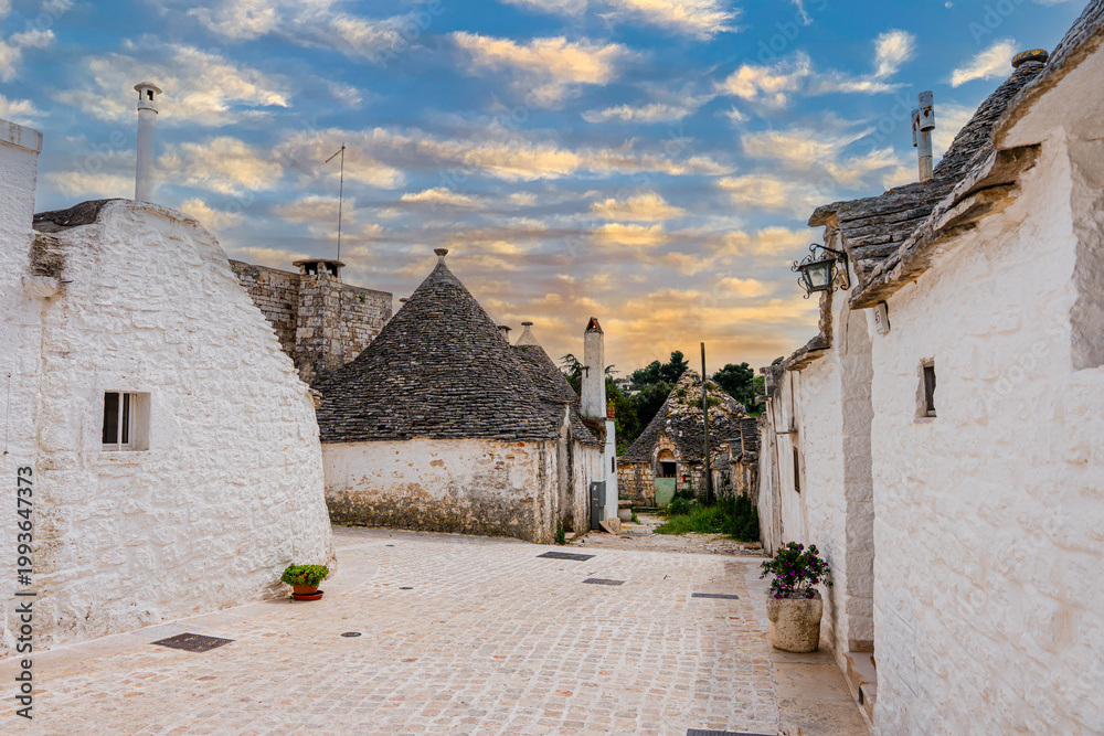 Fototapeta premium Alberobello miasto we Włoszech, słynie z unikatowych form budownictwa – domów typu trulli, które są okrągłe i mają stożkowate dachy z kamienia.
