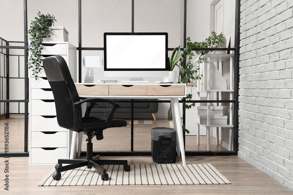 Fototapeta premium Workplace with blank computer monitor near folding screen in office interior