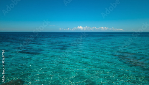 A serene ocean view with clear turquoise water and a blue sky