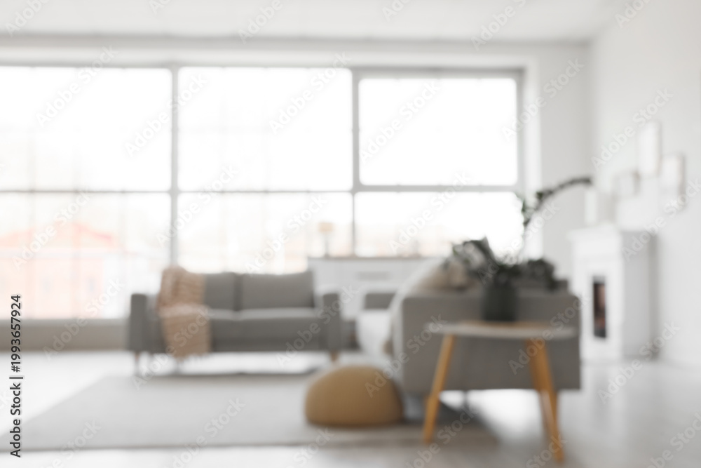 Obraz premium Blurred view of light living room with grey sofas and window