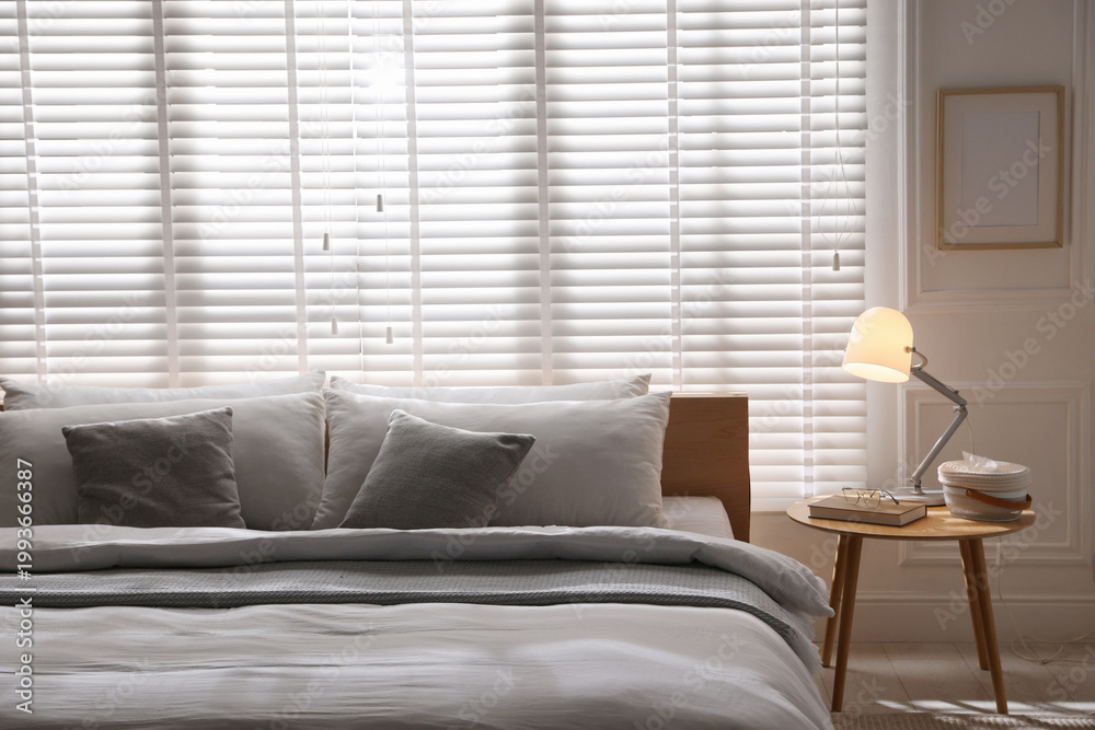 Fototapeta premium Large bed with pillows and blanket near window in room