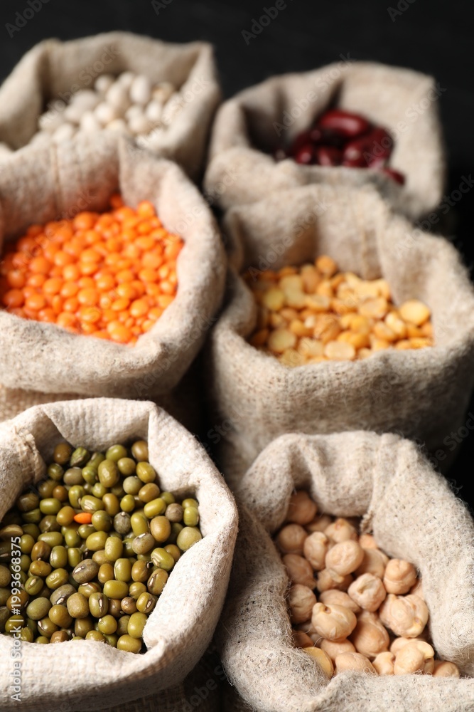 Fototapeta premium Different types of legumes in burlap bags on table, closeup