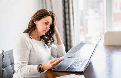 Cuadro en lienzo Senior woman at home kitchen table feeling stressed and confused while looking a