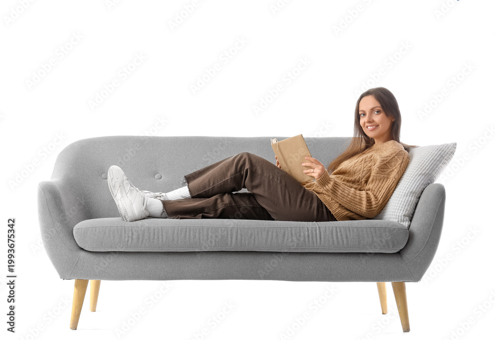 Fototapeta premium Young woman reading book on grey couch against white background