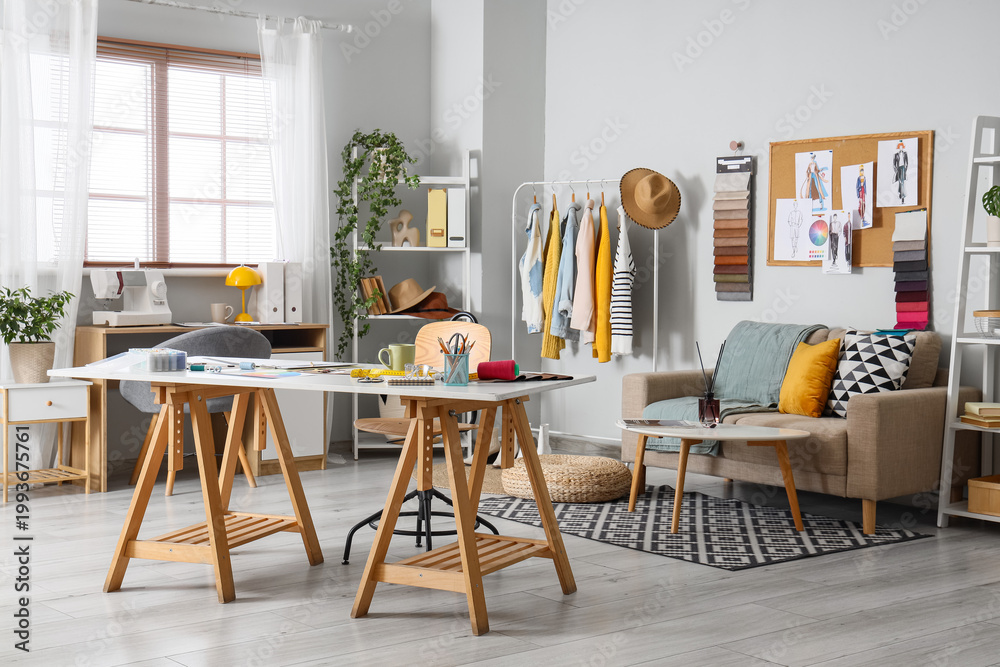 Fototapeta premium Interior of fashion designer's studio with workplace, sofa and clothes rack