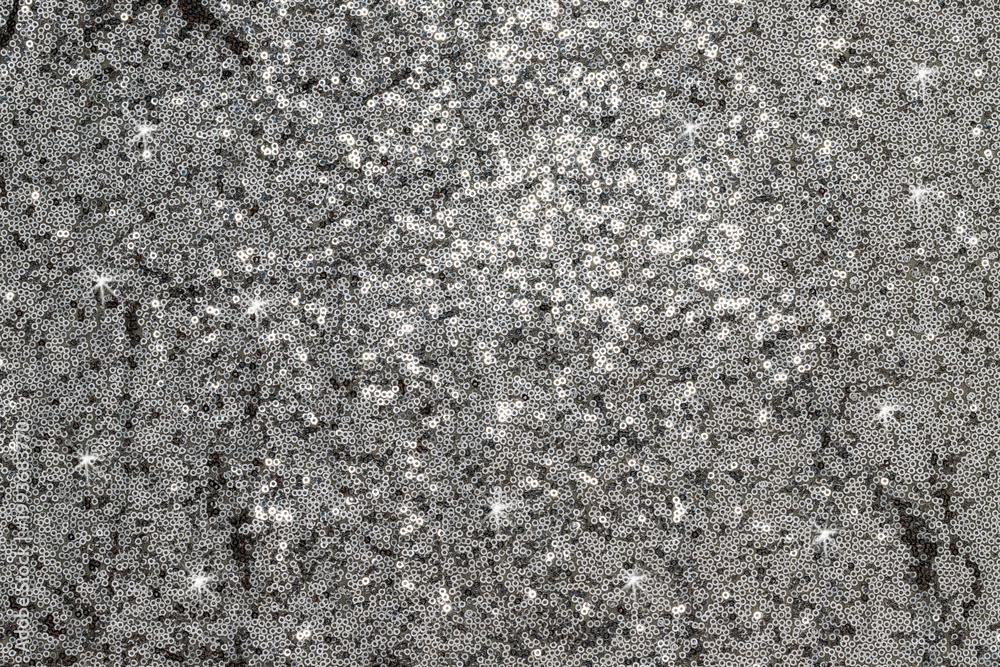 Fototapeta premium Sparkling silver sequins cover a surface and reflect light during a festive event in the evening