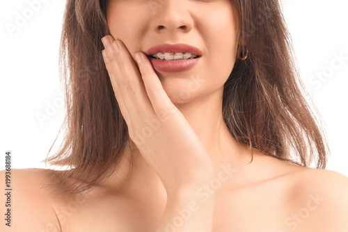 Photography Young woman with dental braces suffering from toothache on white background, clo