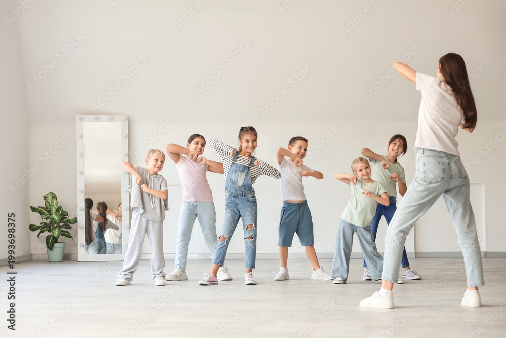 Naklejka premium Group of little children with teacher dancing in studio