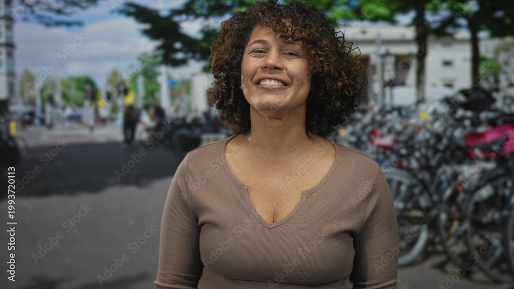 Fototapeta premium Smiling woman beckons with bare hand on bustling street lined with parked bicycles by rack; invitation.