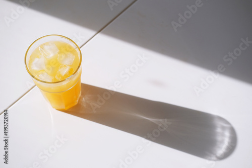 Orange juice in a glass on a bright table with sunlight and shadow, a crisp, refreshing beverage scene perfect for breakfast, cafe, or kitchen branding and lifestyle shoots.