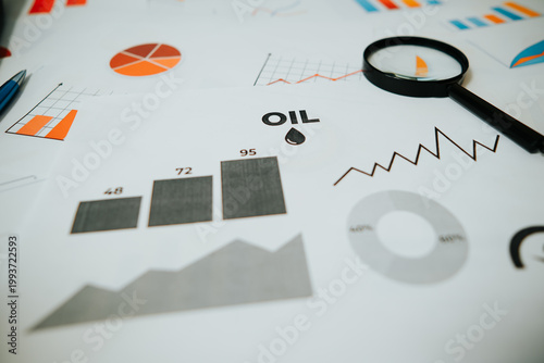 A person examines printed charts and graphs related to financial analysis. The documents include bar graphs and various statistical data points focusing on oil prices