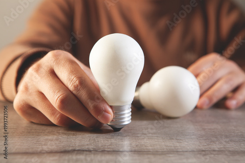 Close up of a person holding a light bulb in his hand.