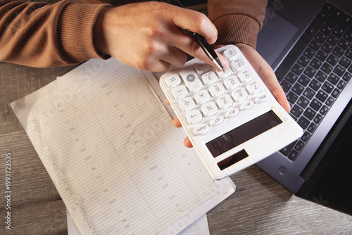 Man working with calculator and laptop on wooden table. Business concept.