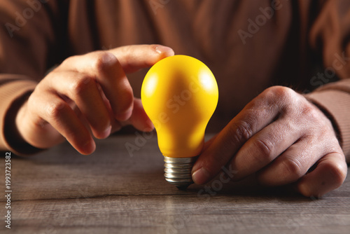 Close up of a person holding a light bulb in his hand.