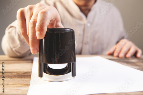 Man holding a black ink bottle on a sheet of white paper.