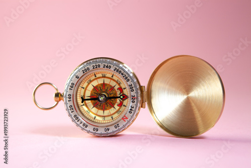 Compass on a pink background. Conceptual image of travel.