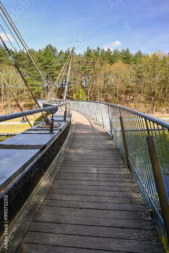 Walkway Leading to a Modern Bridge Over Water With Trees in the Background on a Sunny Day