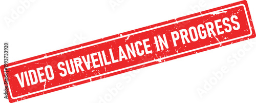 A red rectangular rubber stamp impression displaying the notice VIDEO SURVEILLANCE IN PROGRESS with grunge distressed texture