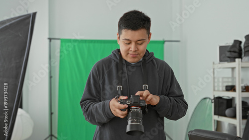 Fotografía Man photographer holding dslr camera, fingers adjusting lens and checking settings in studio; concentration craft