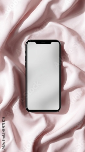 Smartphone mock up on soft pink satin fabric background, featuring a blank screen suitable for design purposes, highlighting a modern mobile device aesthetic