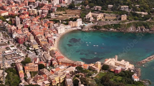 Aerial view of the Bay of Silence with its sandy beach, turquoise water, and colorful historic buildings along the coastline in Sestri Levante, Liguria, Italy.