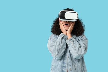 Surprised African-American woman with VR glasses on blue background