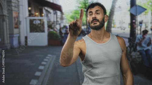 Photos Man holds up hand palm out on street wearing tanktop and beard, stopping approach and signalling refusal; rejection boundary