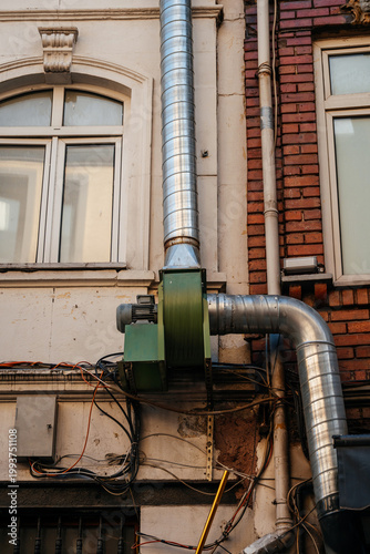 Factory Exhaust View. Aging Brick Building Featuring Ventilation Ducts And Utility Equipment