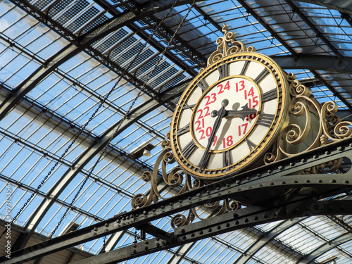 Old fashioned analogue railway station clock inside King's Cross train station showing the time in Roman numerals, London, UK