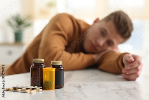 Bild auf Leinwand Depressed man with antidepressant pills at white marble table indoors, selective