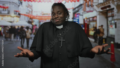Konstfotografi Man priest in black cassock and clerical collar with cross necklace shrugging with palms up on a busy street; bemusement humility