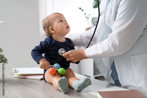 Konstfotografi Young female pediatrician with stethoscope examining cute little baby in clinic