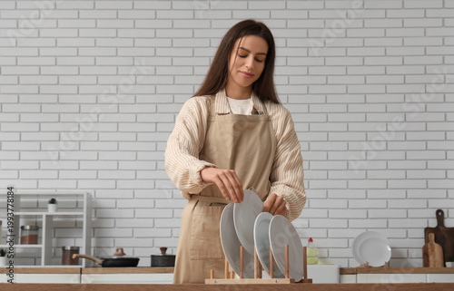 Woman putting clean plates ...