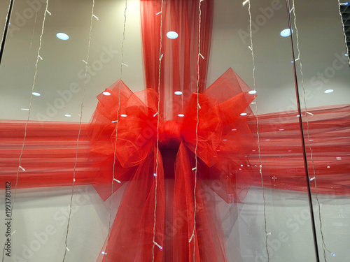 A lush, transparent, festive red bow in the store window. The festive concept.