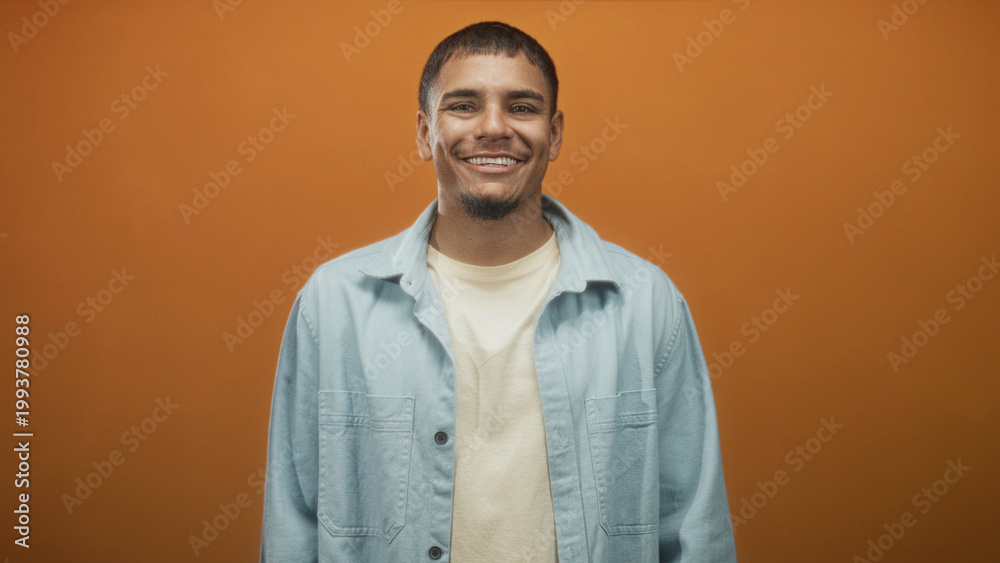 Obraz premium Man looking to side showing face and shoulders in studio wearing light denim jacket and t shirt, subtle smile and direct posture; calm introspection.