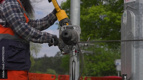 Utility worker operating cable winch on roadside pole