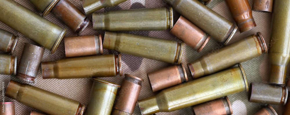 Naklejka premium Big amount of shells cartridges from assault rifle bullets on old camouflage fabric