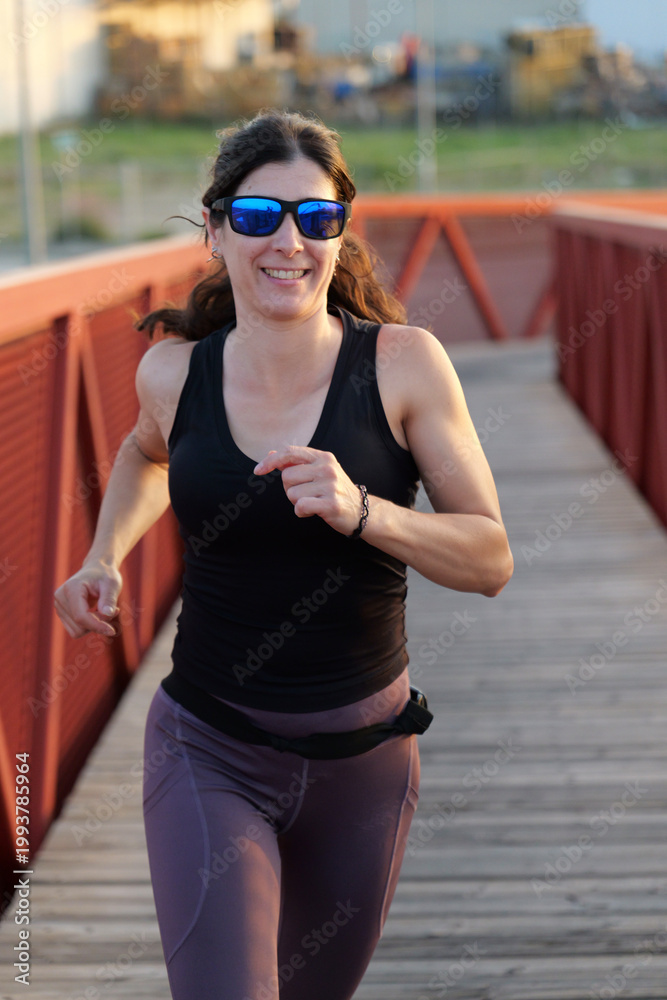 Obraz premium woman with sunglasses running on a bridge