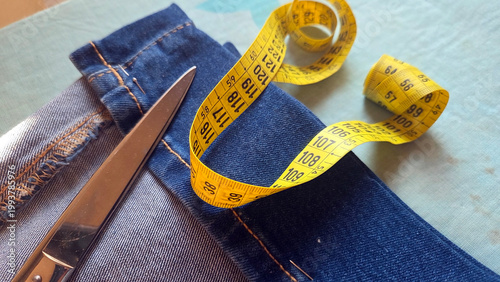 Billede på lærred Closeup of denim jeans with scissors and coiled yellow measuring tape for tailor
