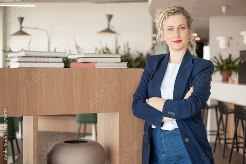 Business woman leaning with arms crossed by shelf in office lobby, confident corporate lifestyle with copy space
