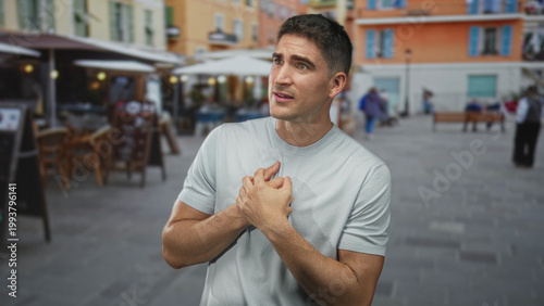 Foto Man clutching chest in heartattack with both hands on a busy street terrace outside a restaurant, gazing upward in distress; anxiety