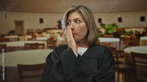Foto Judge in black robe wears round glasses touches chin and looks upward in building; thoughtful reflection doubt pondering