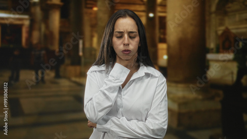 Foto Woman with hand on throat and closed eyes in a church building showing a choking gesture and tense posture; distress