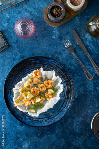 Grilled shrimp skewers with lemon and dill on a blue table