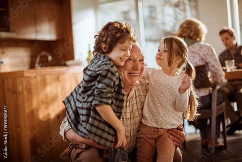 Foto Smiling grandfather hugging grandchildren at home kitchen