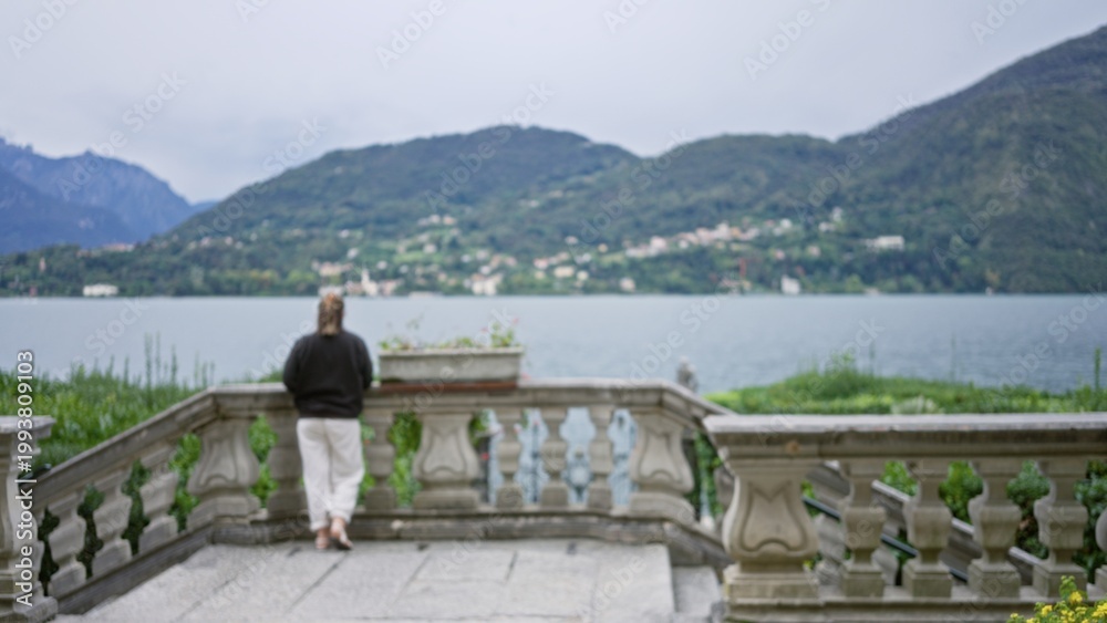 Fototapeta premium Stone terrace balustrade defocused foreground overlooking lake and misty hills, garden; background backdrop copyspace calm.