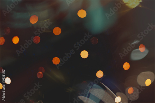 Abstract night scene with warm blurred lights in a bokeh effect, where orange and gold circles of light float on a dark background