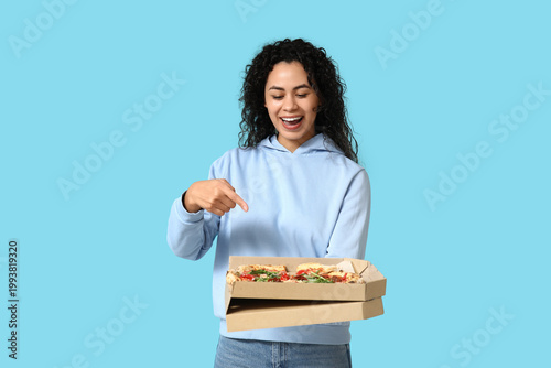 Beautiful young happy African-American woman pointing at delicious pizza on b...